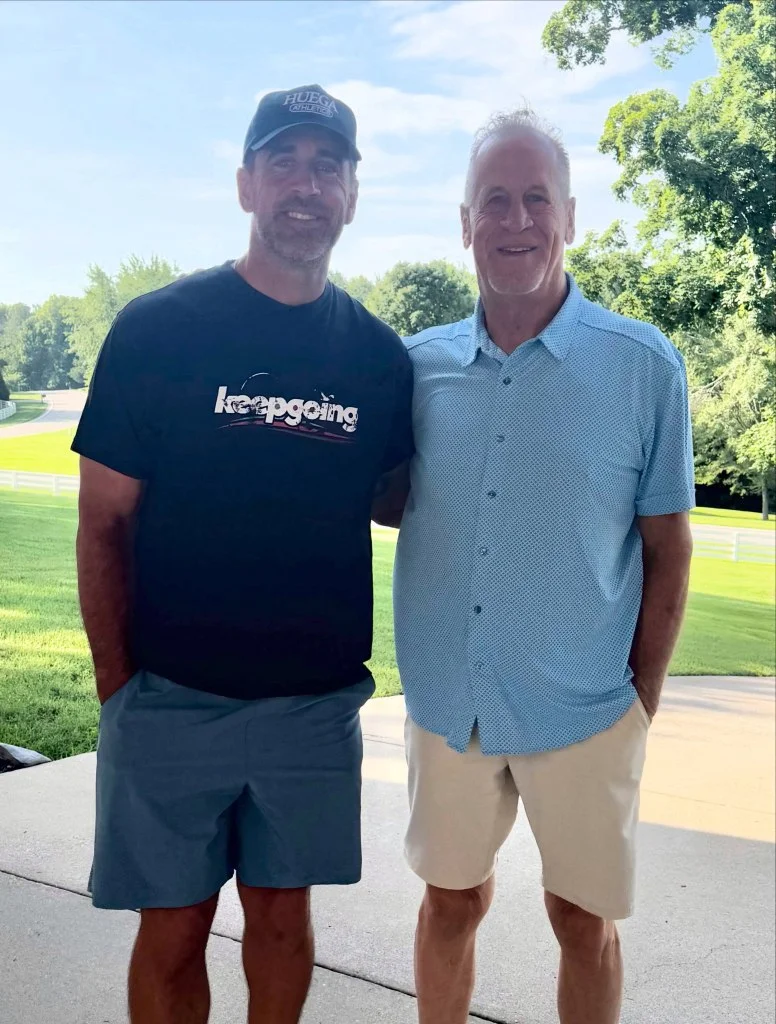Aaron Rodgers with a man, standing outdoors.