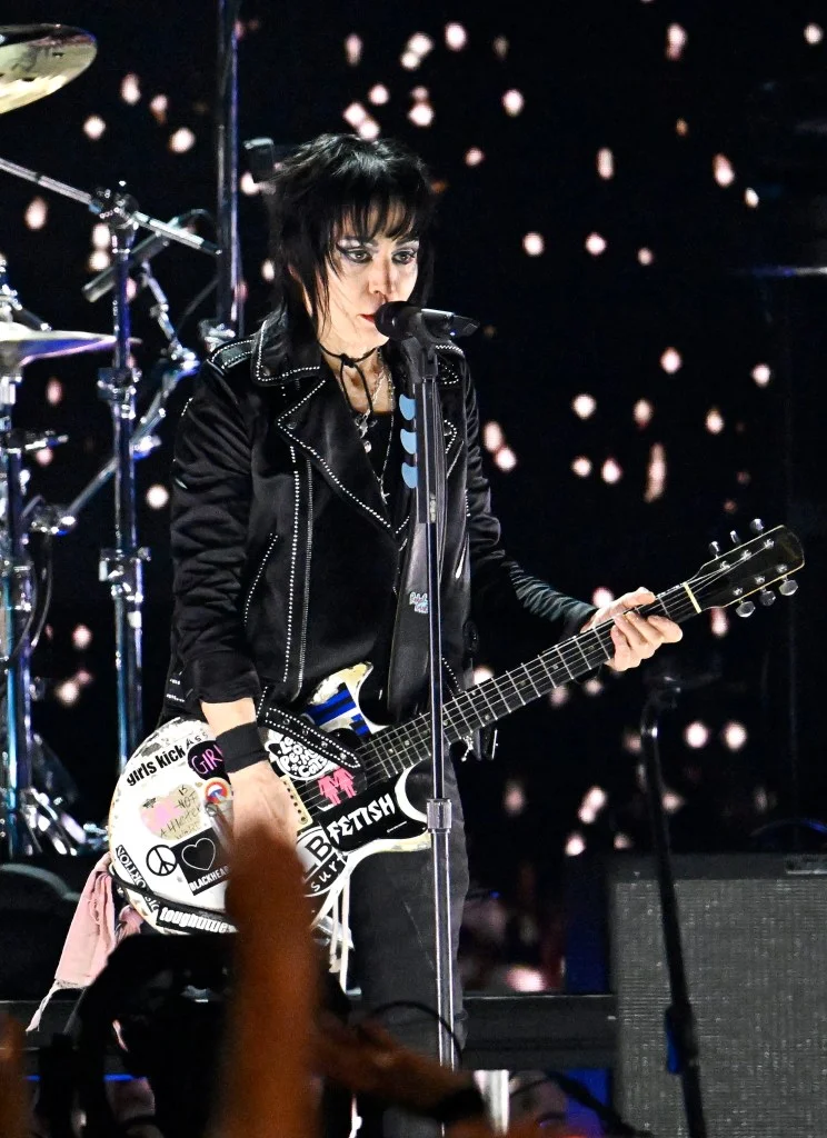 Joan Jett performing live with a guitar and microphone.