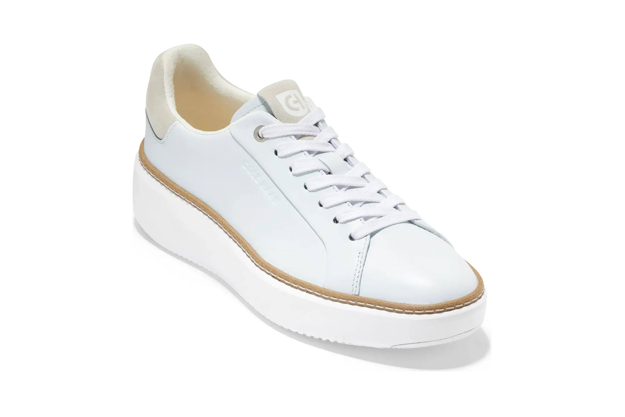 White leather Cole Haan sneaker with a thick white sole and light brown trim.