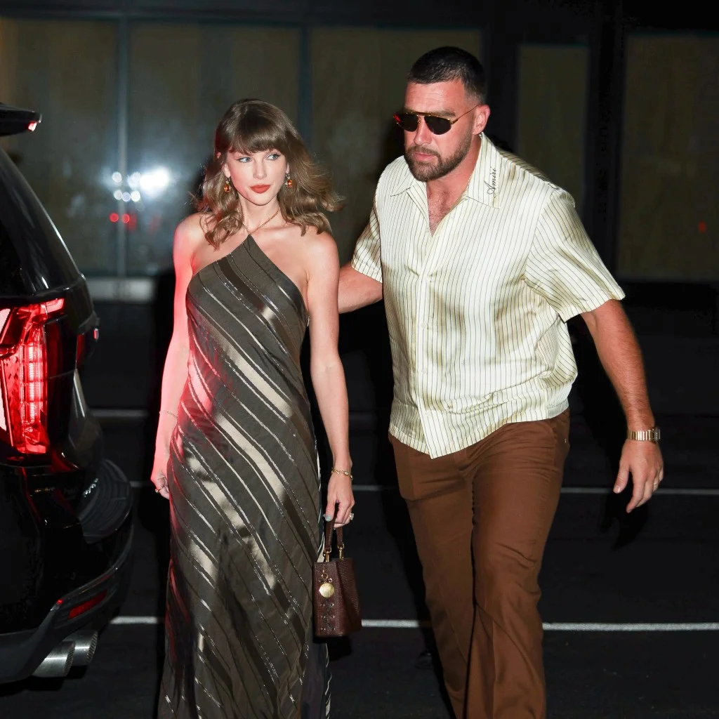 Travis Kelce and Taylor Swift smiling at each other at an awards show.