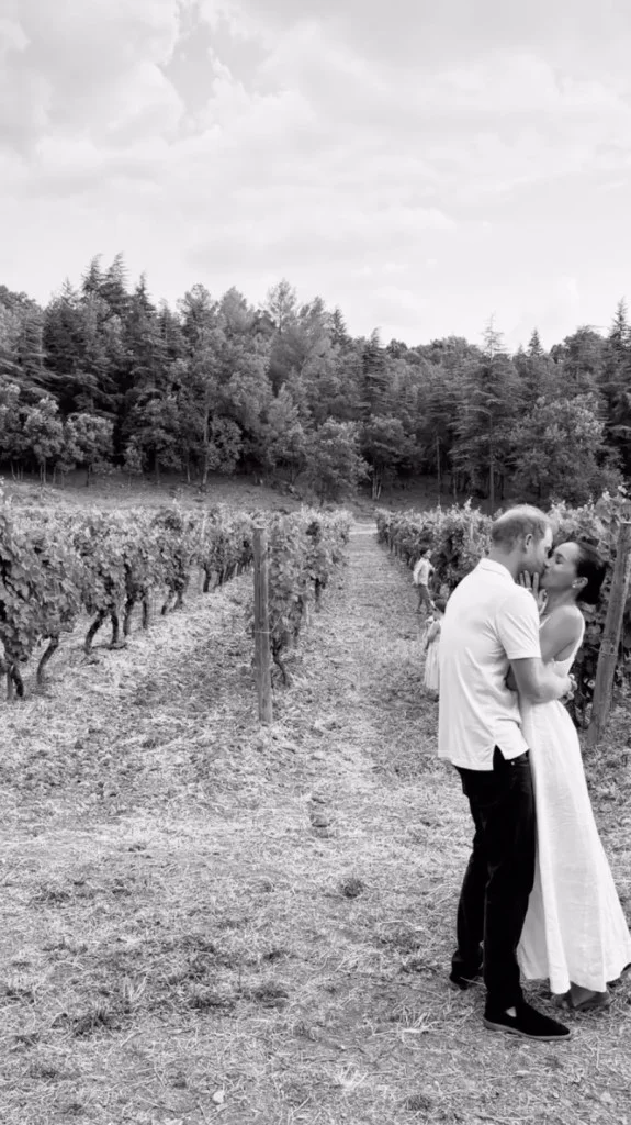 Black and white photo of Prince Harry and Meghan Markle kissing in a vineyard.