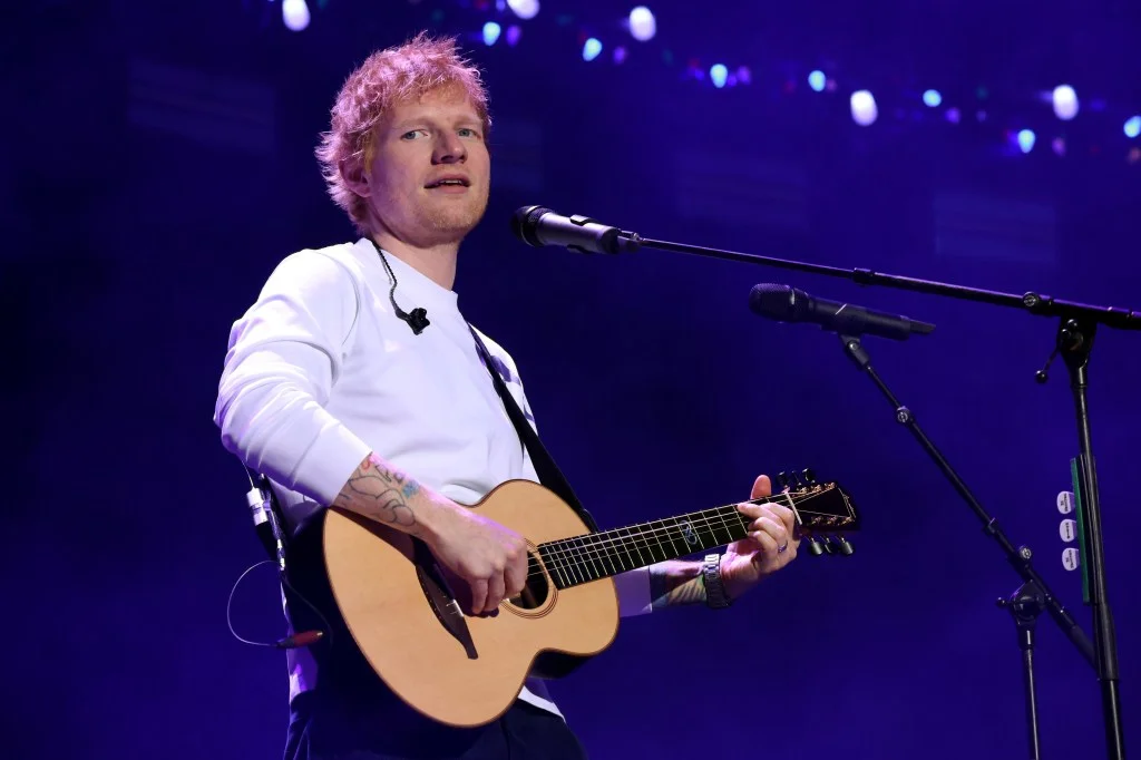 Ed Sheeran performing with an acoustic guitar and microphone at iHeartRadio Z100's Jingle Ball.