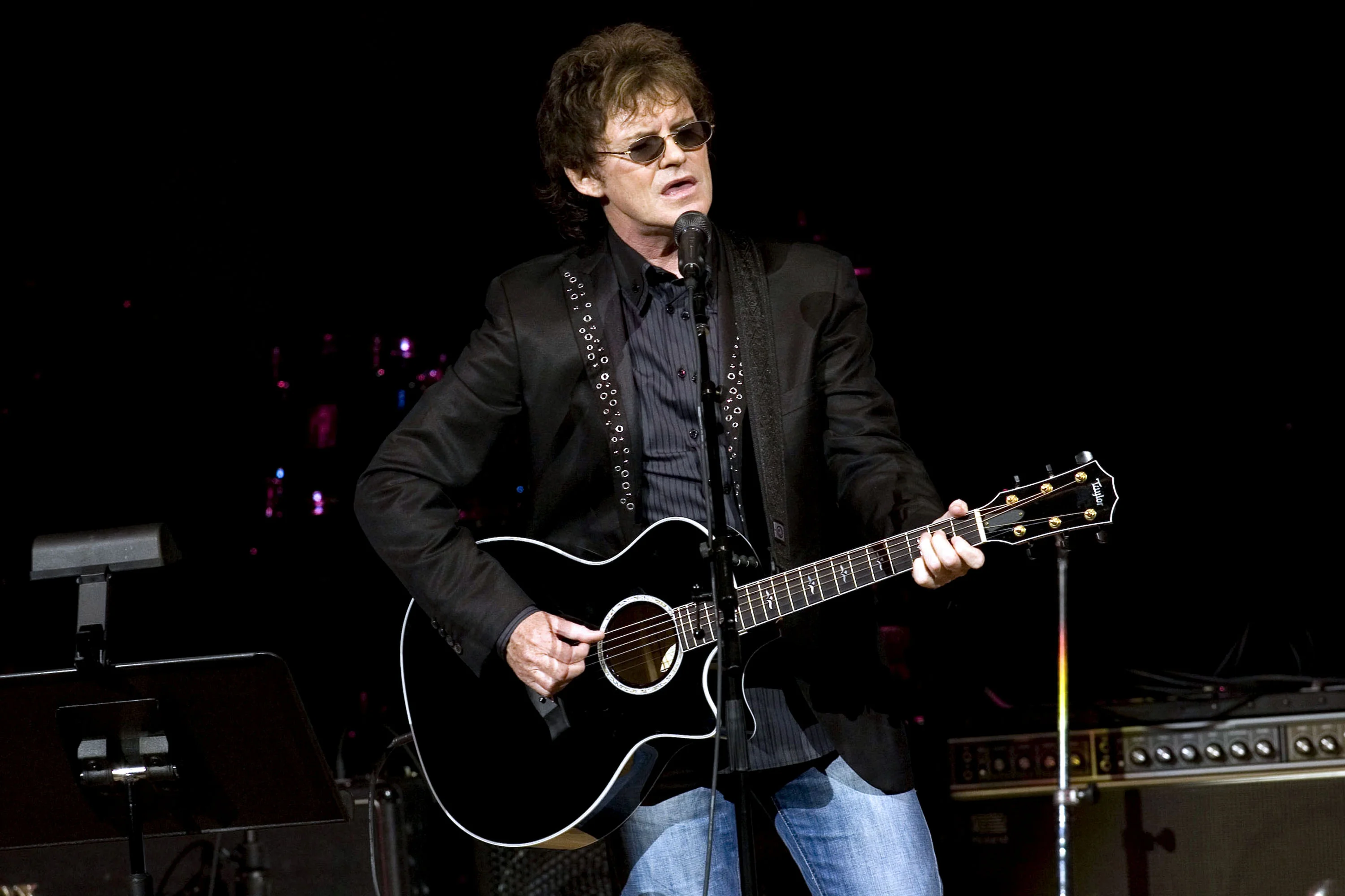 Pete Byrne performing with a black acoustic guitar.